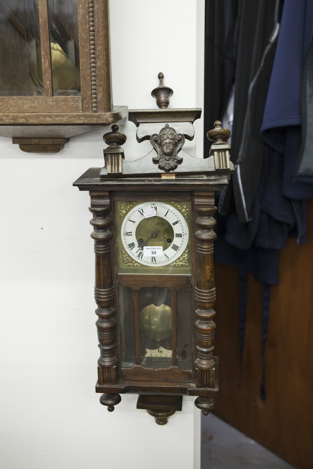 A VIENNA WALL CLOCK, BRASS FACE WITH CREAM CHAPTER RING, BLACK ROMAN NUMERALS, TYPICAL CASE WITH