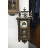A VIENNA WALL CLOCK, BRASS FACE WITH CREAM CHAPTER RING, BLACK ROMAN NUMERALS, TYPICAL CASE WITH