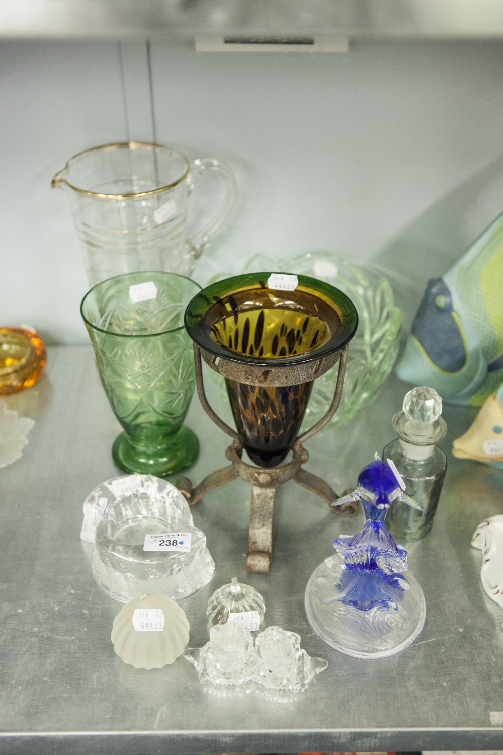 A COLOURED GLASS TRUMPET VASE ON METAL STAND, A COLOURED GLASS DOLPHIN ORNAMENT AND THREE OTHER