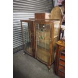 A TWO DOOR GLASS DISPLAY CABINET WITH COLOURED GLASS PANELS AND ORIENTAL DECORATION (A.F.)