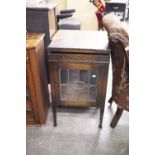 AN OAK SMALL DISPLAY CABINET, WITH GLAZED AND LEADED DOOR AND LIFT UP TOP TO REVEAL A CANTEEN OF