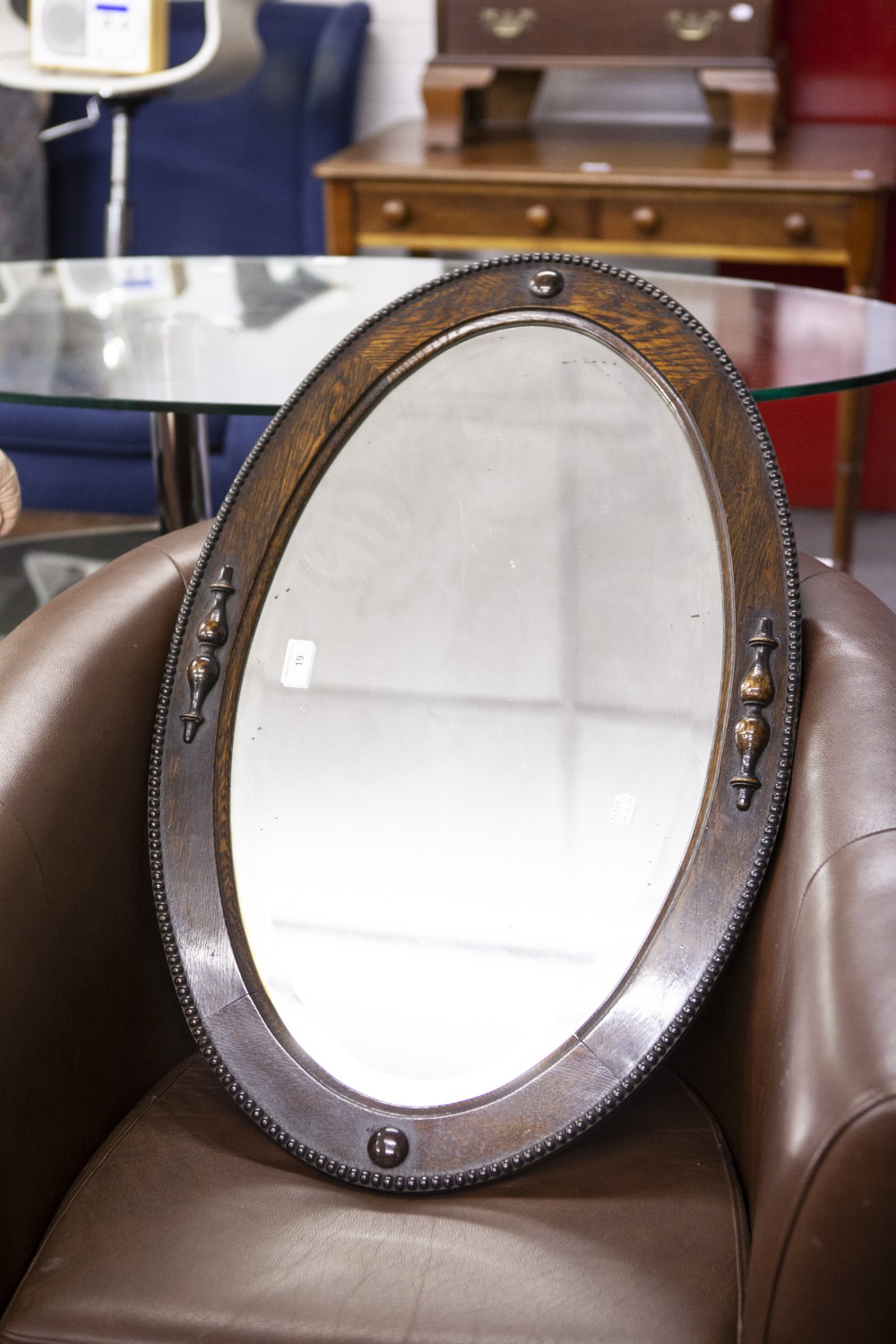 AN OVAL BEVELLED EDGE WALL MIRROR, IN OAK FRAME