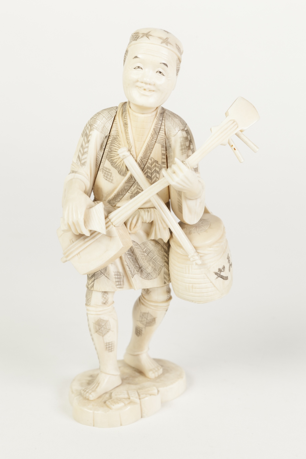 A JAPANESE MEIJI PERIOD CARVED SECTIONAL IVORY FIGURE holding a stringed musical instrument and