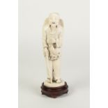 A JAPANESE MEIJI PERIOD ONE PIECE CARVED IVORY OKIMONO OF AN AGED BEARDED MAN, holding a