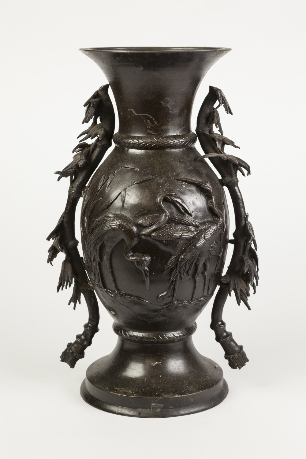 AN EARLY TWENTIETH CENTURY JAPANESE PATINATED BRONZE VASE, cast in relief with cranes amongst