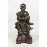 A CHINESE QING DYNASTY PATINATED BRONZE FIGURE OF A BUDDHISTIC DISCIPLE, sat upon a stepped base his