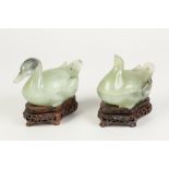 A PAIR OF LATE NINETEENTH/EARLY TWENTIETH CENTURY CHINESE CARVED ALE GREEN HARDSTONE DUCKS FORMING