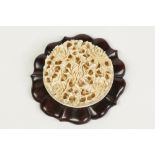 A CHINESE LATE QING DYNASTY CANTON CARVED AND PIERCED IVORY ROUNDEL, with peony and