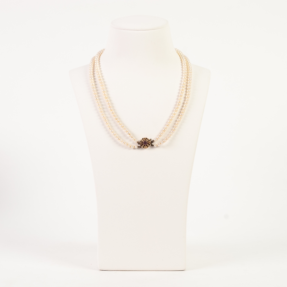 A TWO STRAND NECKLACE OF GRADUATED CULTURED PEARLS with 9ct gold pierced flower pattern clasp, set