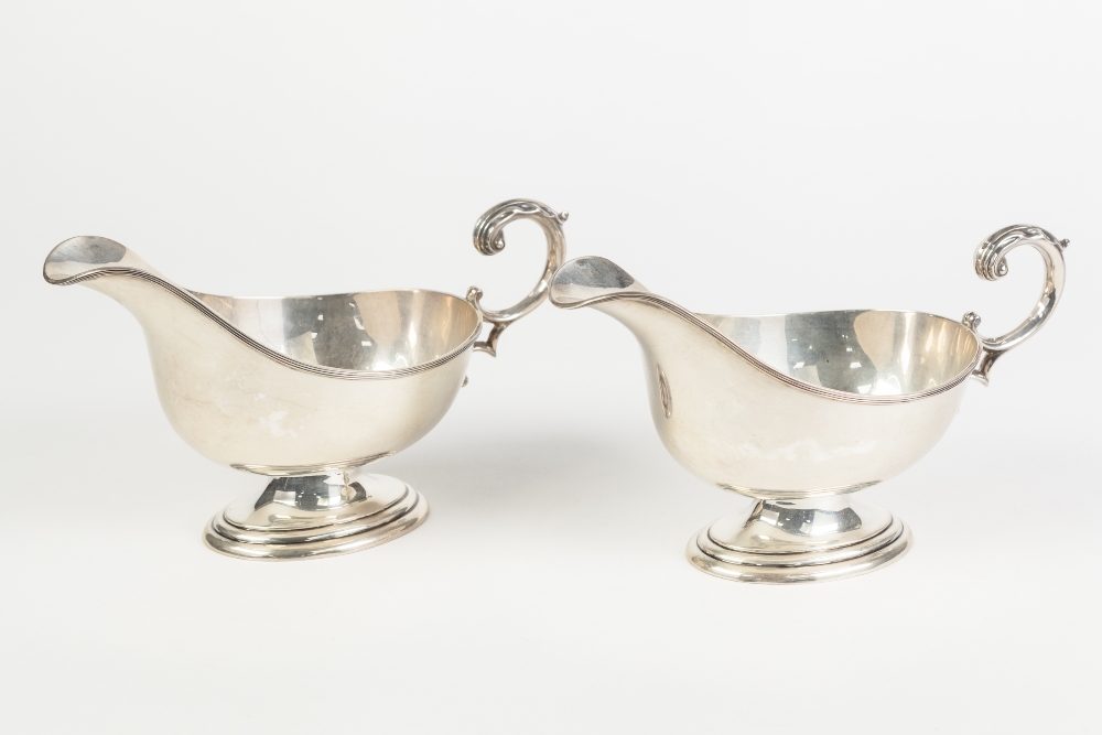 A PAIR OF PRE-WAR SILVER SAUCE BOATS, with leaf capped flying scroll handles, on oval pedestal
