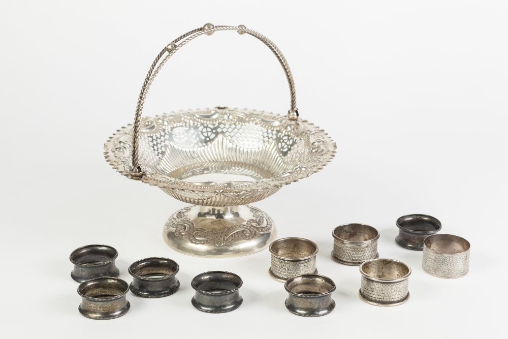 A LATE VICTORIAN SILVER STAMPED AND PIERCED SWING HANDLED CAKE BASKET, on a circular domed