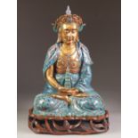 A CHINESE LATE QING/REPUBLIC PERIOD PORCELAIN MODEL OF A BUDDHA seated cross legged holding in the