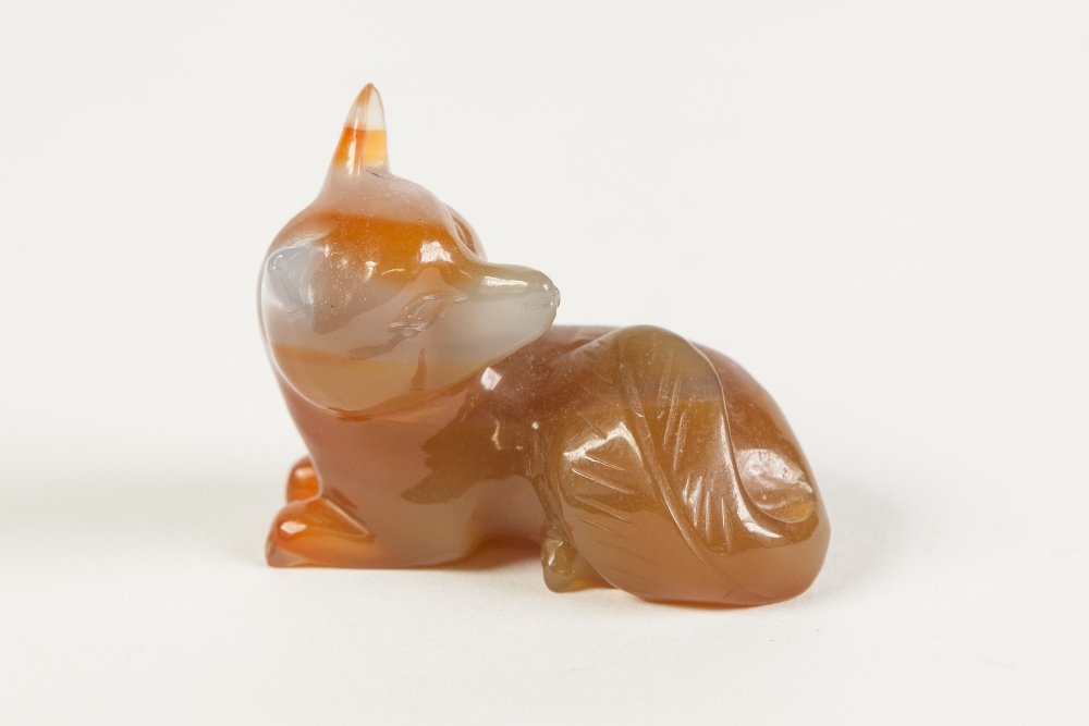 A CHINESE SMALL GREY AND RUSSET COLOURED JADE MODEL OF A RECUMBENT FOX, 2" (5cm) long