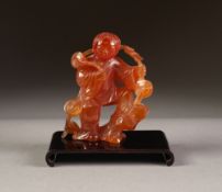 ORIENTAL CARVED ROSE QUARTZ FIGURE, modelled as a man standing, with left leg raised on a rocky