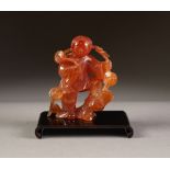 ORIENTAL CARVED ROSE QUARTZ FIGURE, modelled as a man standing, with left leg raised on a rocky