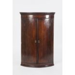 LATE EIGHTEENTH CENTURY OAK AND MAHOGANY CROSSBANDED BOW FRONTED CORNER CUPBOARD, of typical form