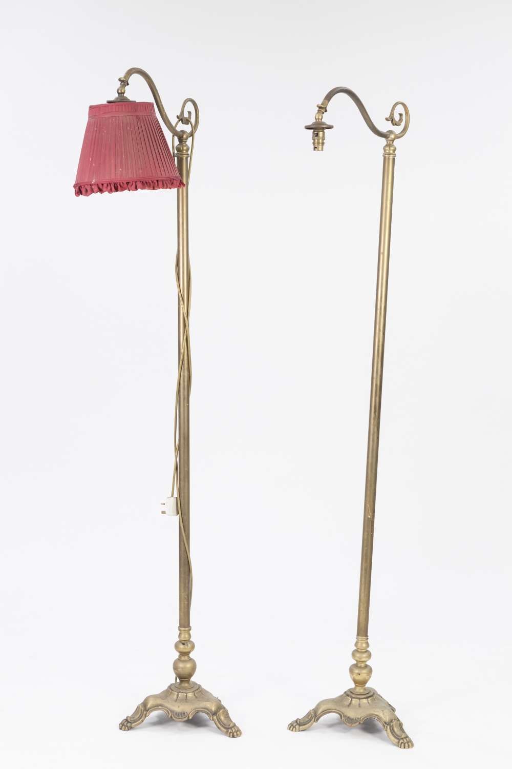 PAIR OF EDWARDIAN BRASS STANDARD LAMPS, each with plain column, scroll arm and tri form base with