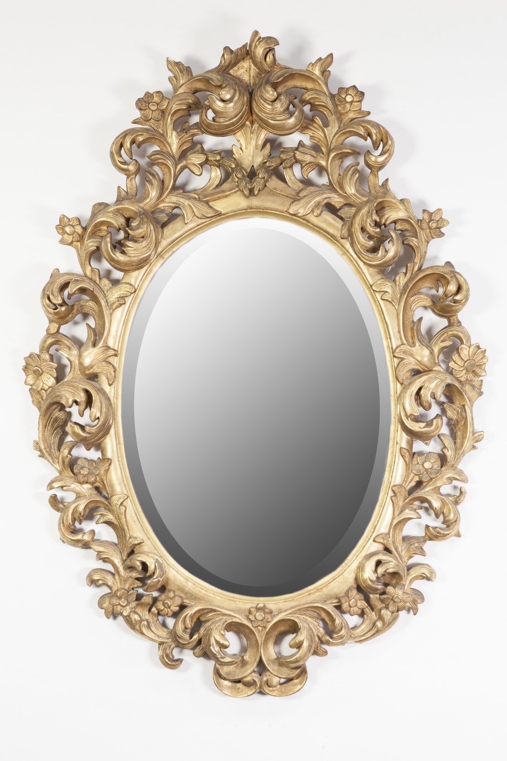 VICTORIAN CARVED GILTWOOD WALL MIRROR, the bevel edged oval plate within a pierced frame carved in