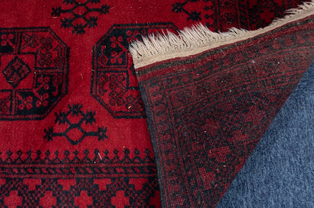 TURKOMAN AFGHAN RUG with two rows of four black stencilled octagonal guls on a crimson field, - Image 2 of 3