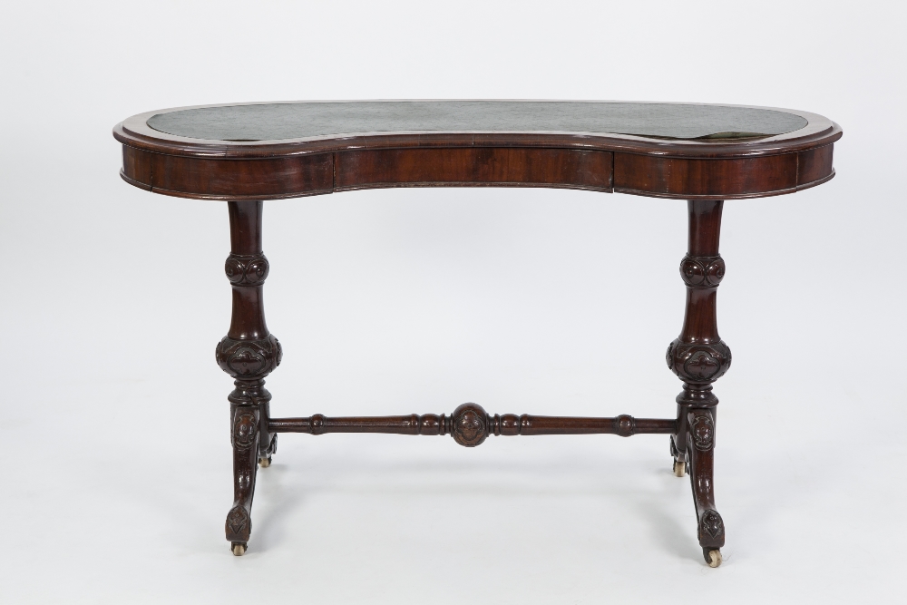 VICTORIAN CARVED MAHOGANY KIDNEY SHAPED WRITING TABLE, the crossbanded top with later faux green