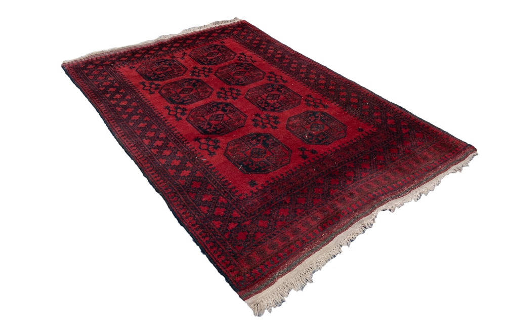 TURKOMAN AFGHAN RUG with two rows of four black stencilled octagonal guls on a crimson field,