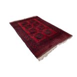 TURKOMAN AFGHAN RUG with two rows of four black stencilled octagonal guls on a crimson field,