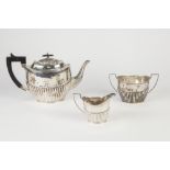 GEORGE V THREE PIECE SILVER TEA SET, of oval, part fluted form with angular scroll handles and