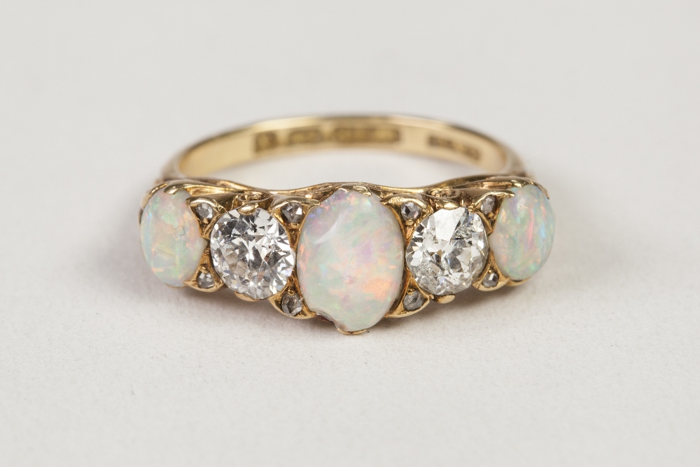 VICTORIAN 18ct GOLD, DIAMOND AND OPAL RING, with a carved setting of three oval opals, two round old