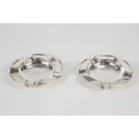 PAIR OF GEORGE V SILVER ASHTRAYS, each of circular form with four rests and raised border, 4 3/8" (