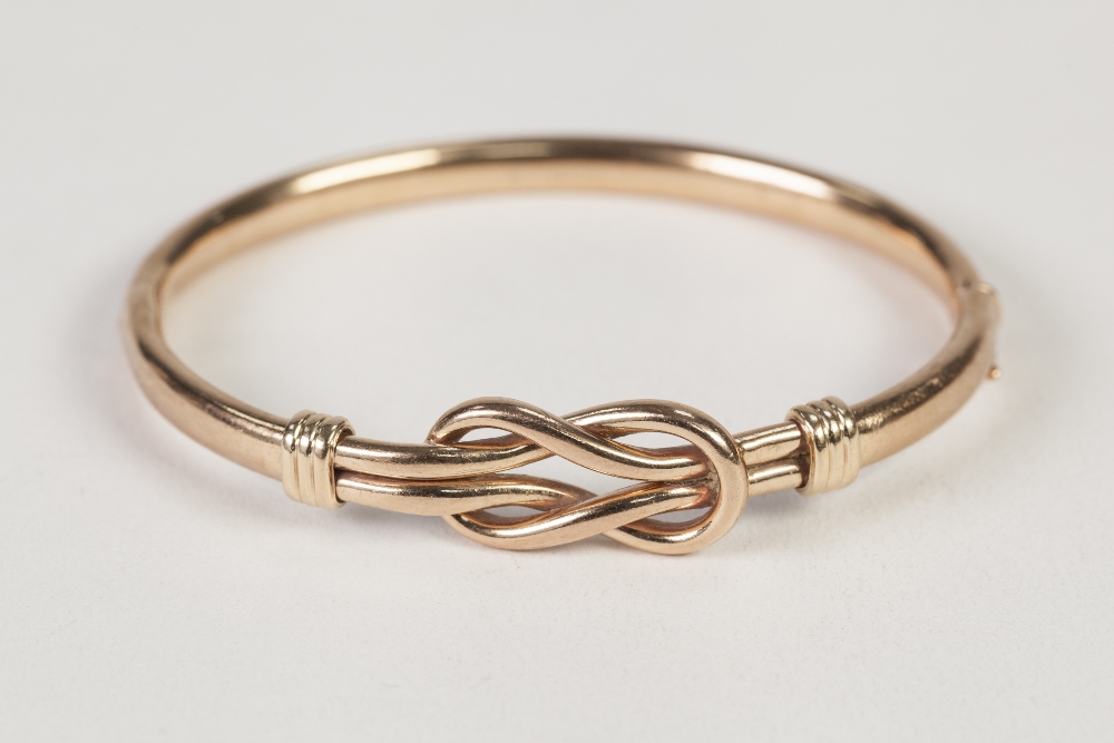 9ct GOLD HOLLOW, HINGE OPENING BANGLE, with 'loose knot' pattern top, 12.3gms