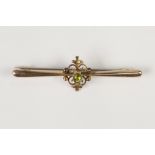 9ct GOLD PROPELLER SHAPED BAR BROOCH, the open scroll work centre collet set with an oval pale