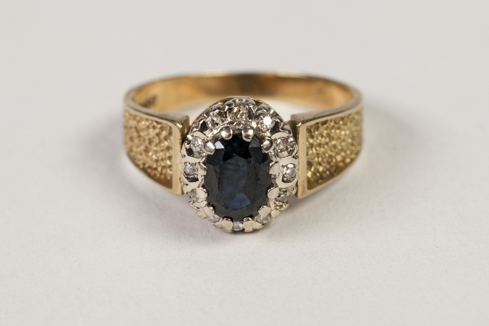 TEXTURED 18ct GOLD, SAPPHIRE AND DIAMOND CLUSTER RING, set with an oval sapphire and surround of