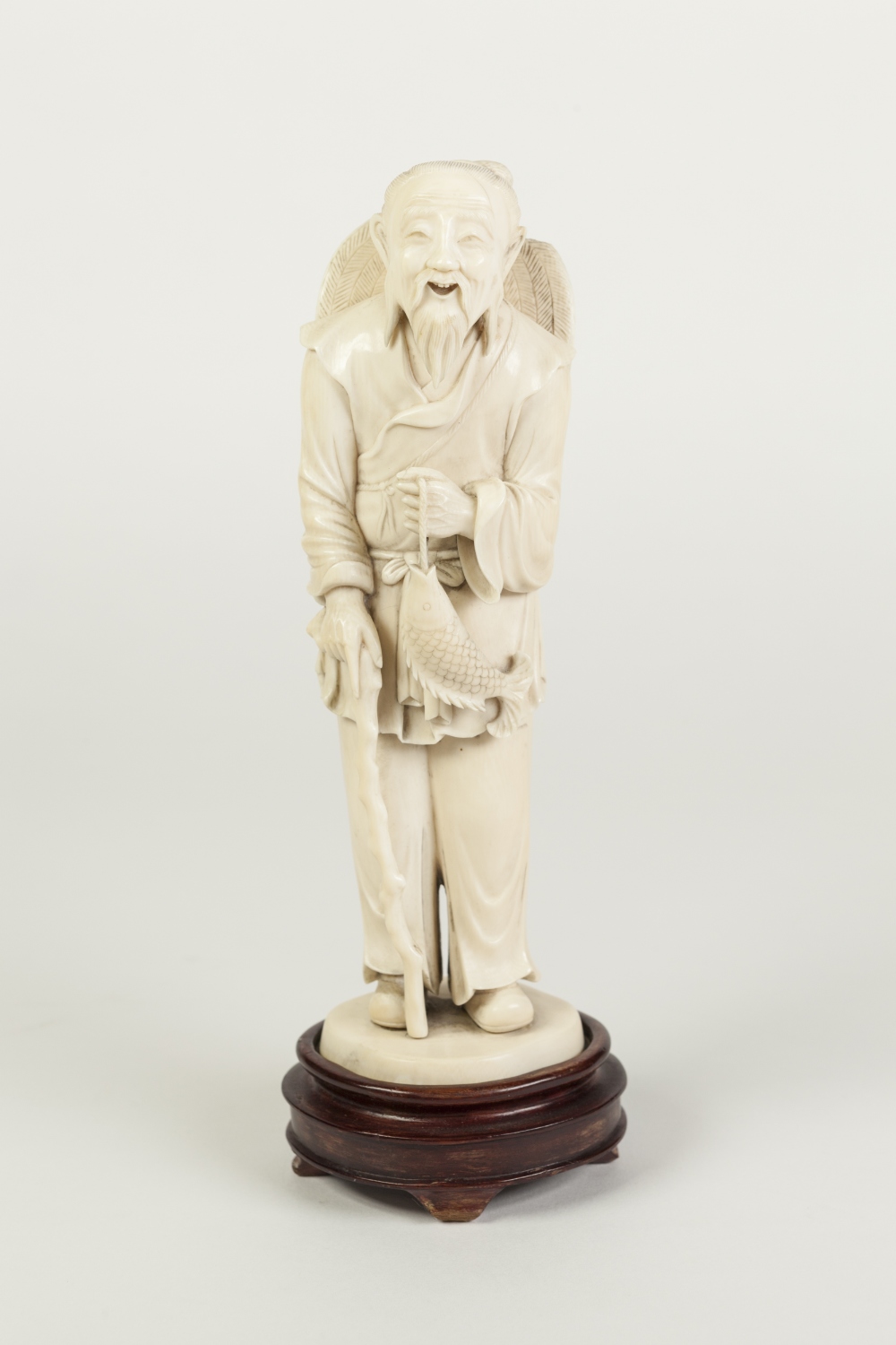 AN EARLY TWENTIETH CENTURY JAPANESE ONE PIECE CARVED IVORY OKIMONO OF AN AGED BEARDED MAN, holding a