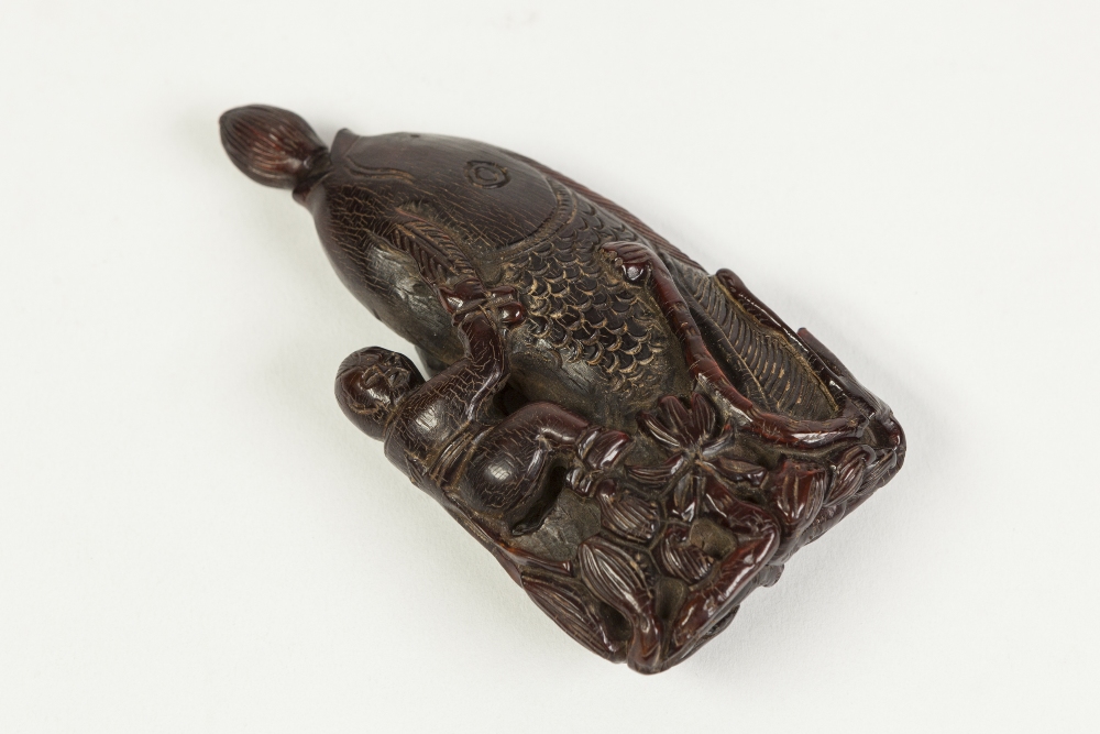 AN AGED CHINESE QING DYNASTY CARVED HORN SNUFF BOTTLE, formed of a small figure astride a carp