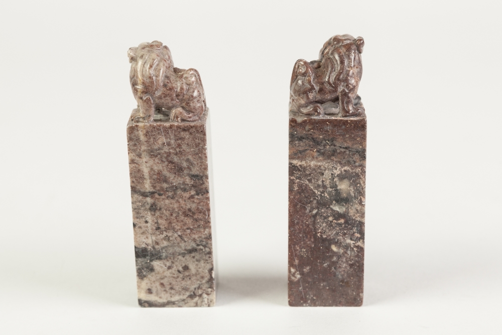 A NEAR PAIR OF CHINESE MOTTLED PURPLISH HARDSTONE SQUARE SEALS, surmounted with Buddhistic lions, - Image 2 of 2