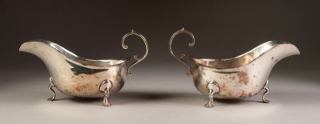 PAIR OF INTER-WAR YEARS SILVER SAUCE BOATS with cut rims and flying scroll handles, each standing on
