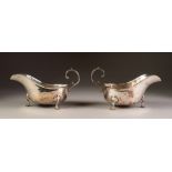 PAIR OF INTER-WAR YEARS SILVER SAUCE BOATS with cut rims and flying scroll handles, each standing on