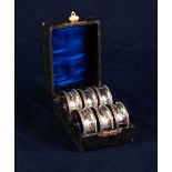 EARLY 20th CENTURY CASED SET OF SIX SILVER NAPKIN RINGS with beaded borders and foliate scroll