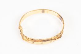 EDWARDIAN 9ct GOLD HOLLOW BANGLE, hinge opening, the top with raised lozenge shaped panel star set