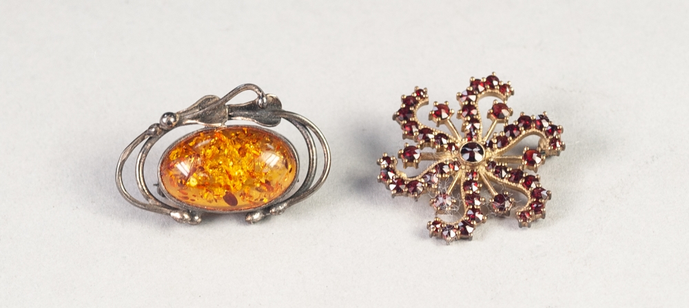 SILVER OPENWORK BROOCH, set with a golden amber oval cabochon and a GARNET WHORL PATTERN BROOCH