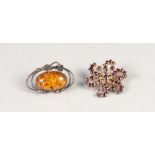 SILVER OPENWORK BROOCH, set with a golden amber oval cabochon and a GARNET WHORL PATTERN BROOCH