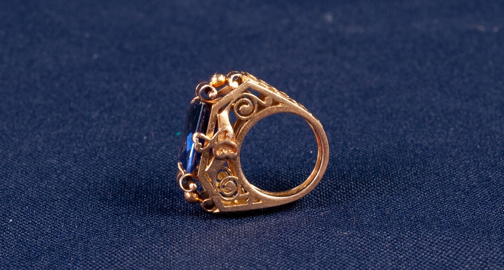 GOLD AND SYNTHETIC SAPPHIRE DRESS RING with an emerald cut sapphire, in a four claw setting with - Image 2 of 2