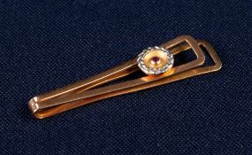 GOLD COLOURED METAL TIE CLIP with applied disc with white wreath border and centre tiny collet set