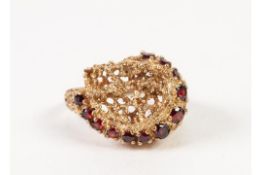 9ct GOLD PIERCED NUGGET PATTERN COCKTAIL RING, set with a curved row of twelve small rubies, 6.5gms,