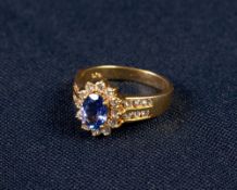 18ct GOLD TANZANITE AND DIAMOND CLUSTER RING, set with an oval tantanzite of medium deep bluish