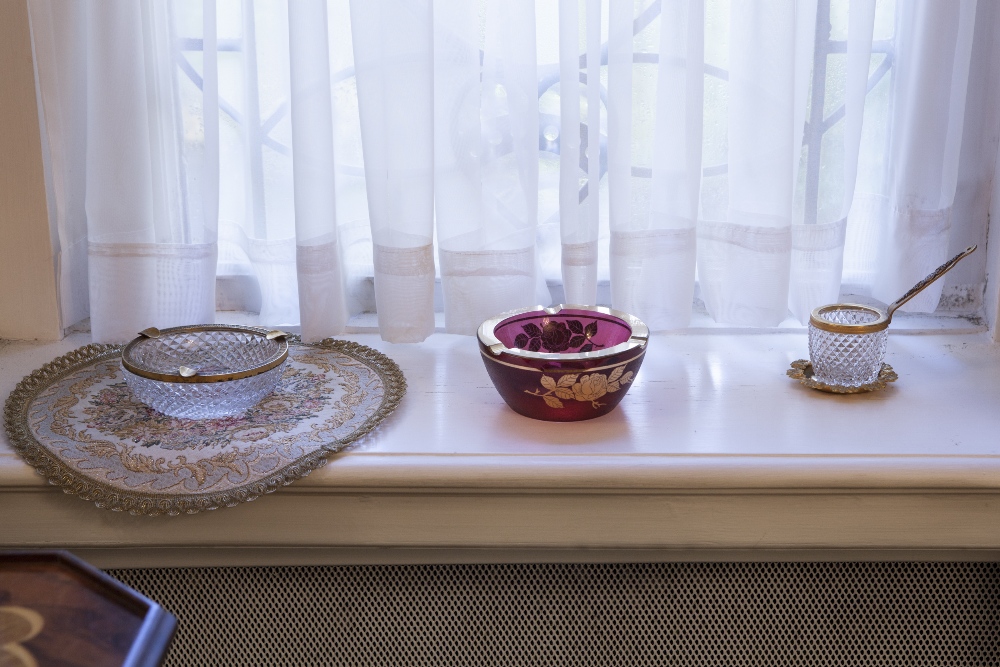 A GILT METAL AND GLASS CIGARETTE DISPENSER ON STAND, WITH MATCHING LARGE CIRCULAR ASHTRAY; A RUBY