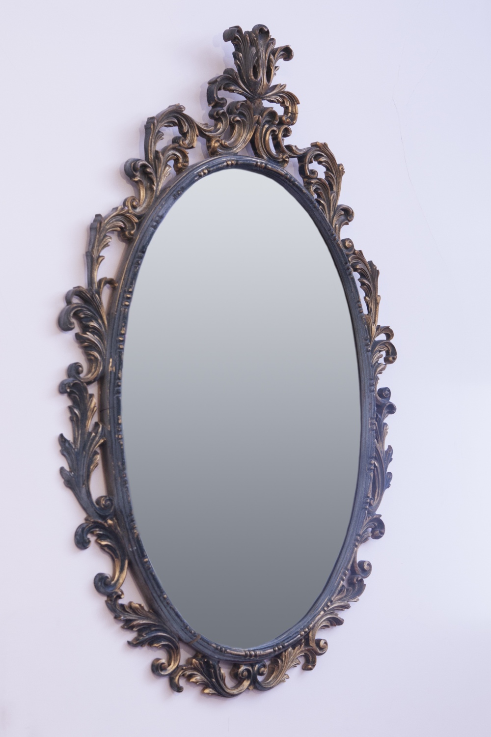 AN OVAL BEVELLED EDGE WALL MIRROR IN CARVED AND GILT WOOD FOLIATE SCROLL FRAME, 3'2" HIGH OVERALL (