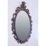 AN OVAL BEVELLED EDGE WALL MIRROR IN CARVED AND GILT WOOD FOLIATE SCROLL FRAME, 3'2" HIGH OVERALL (