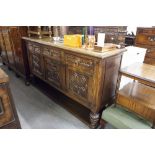 A LARGE OAK SIDEBOARD, THREE DRAWER ABOVE THREE CUPBOARD DOORS WITH CARVED PANELS AND A LOW RAISED