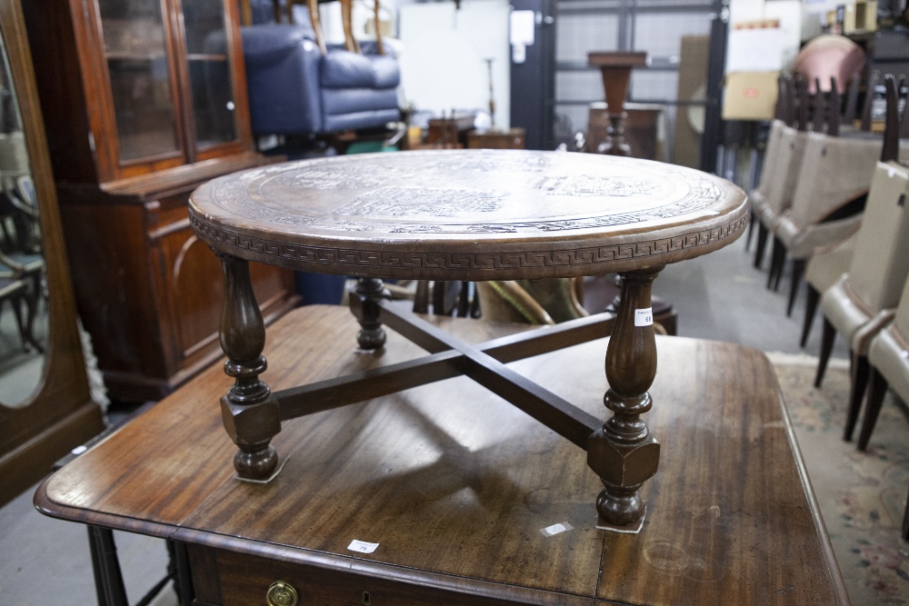 A ROUND COFFEE TABLE, 34 1/2" DIAMETER, WOOD COVERED IN LEATHER CARVED WITH INCAN MOTIFS, MADE IN